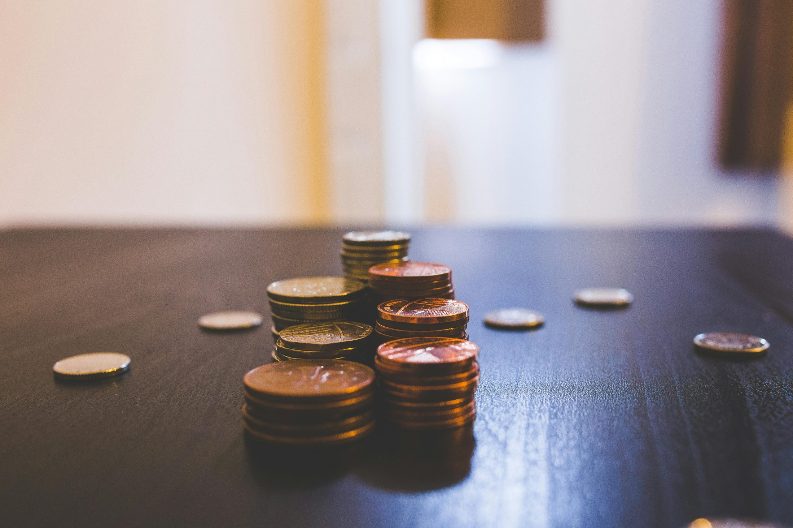 Close-up of various coins stacked on a dark table indoors.